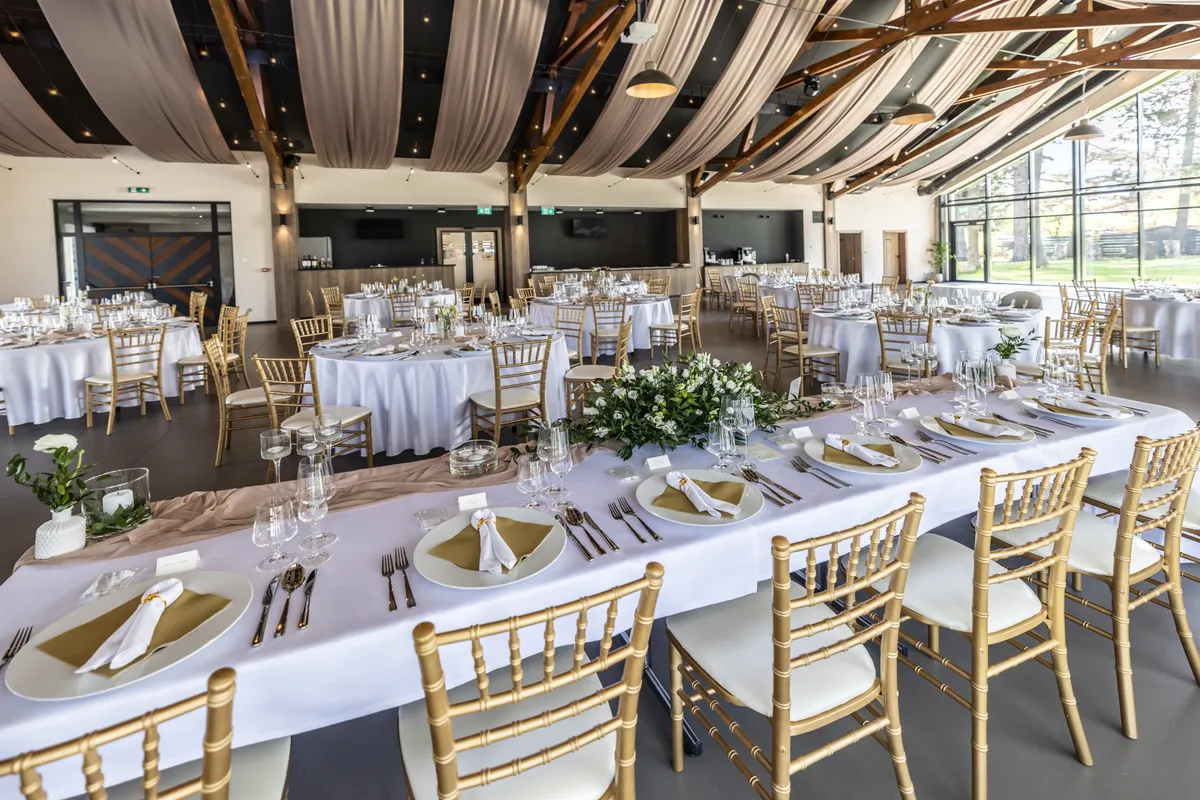 Wedding reception venue with round tables, white linens, and floral centrepieces