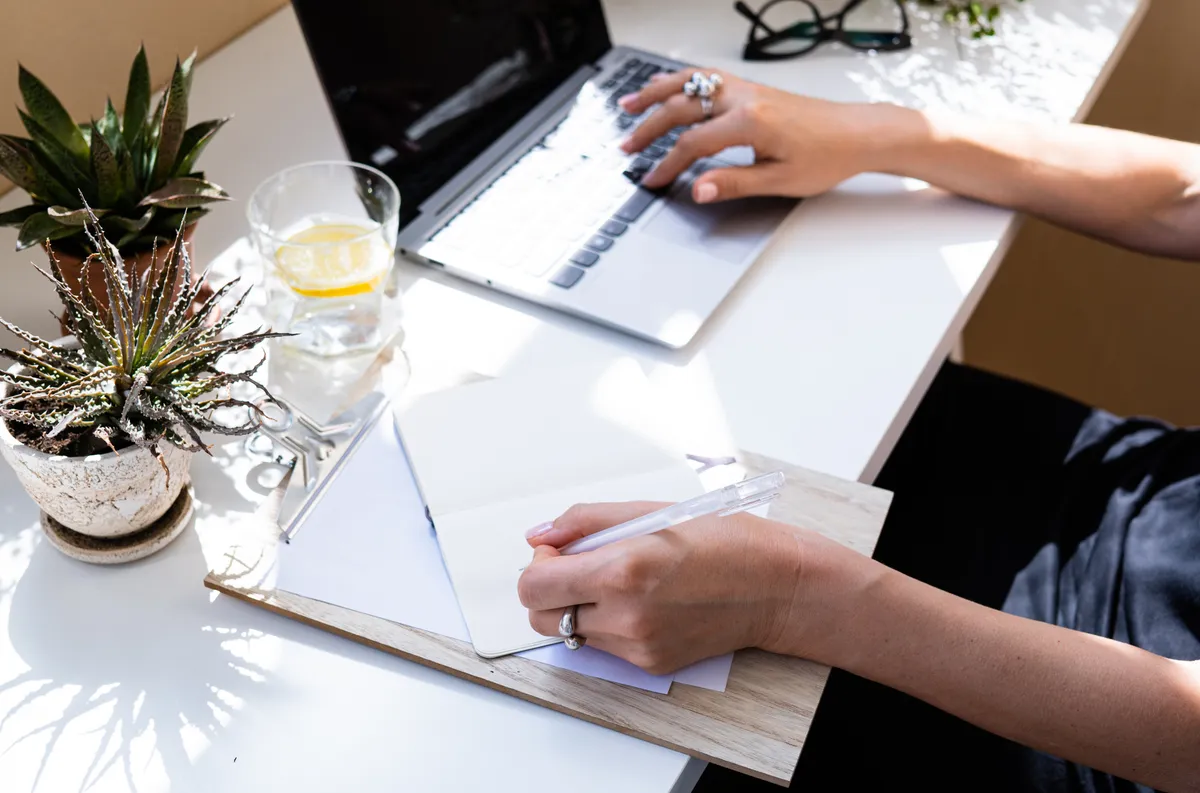 Person planning an event at a desk with laptop, phone, and printed guest list