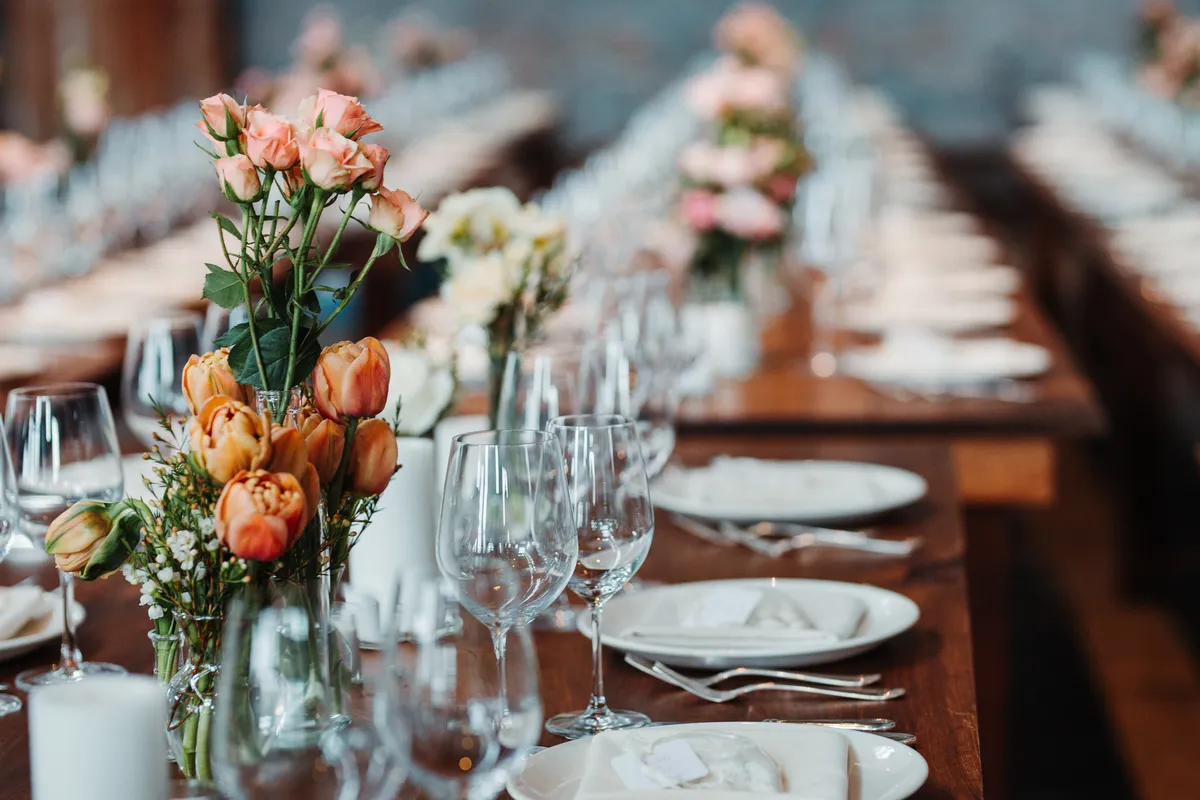 A long wedding reception banquet table set with candles, glassware and florals
