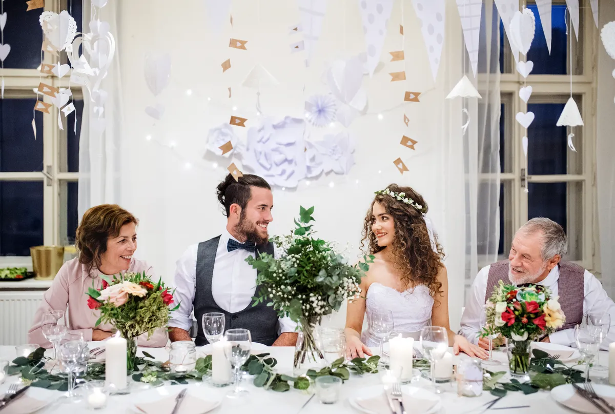 A bride and groom standing with grandparents at a wedding reception